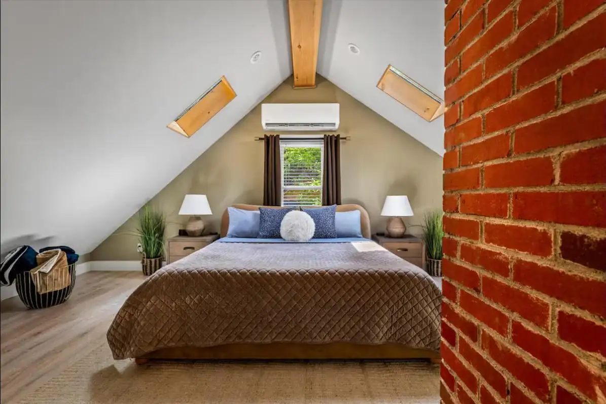 Attic bedroom with smooth vaulted ceilings, skylights, exposed beam, and brick chimney