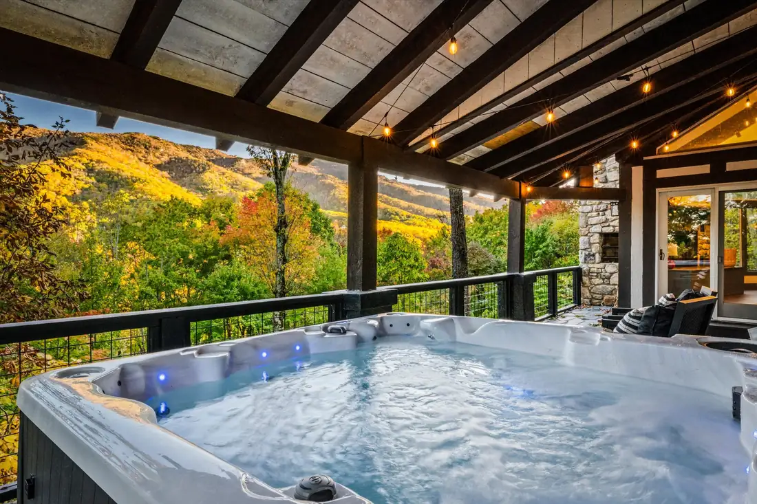 Hot tub under a covered porch overlooking autumn mountains