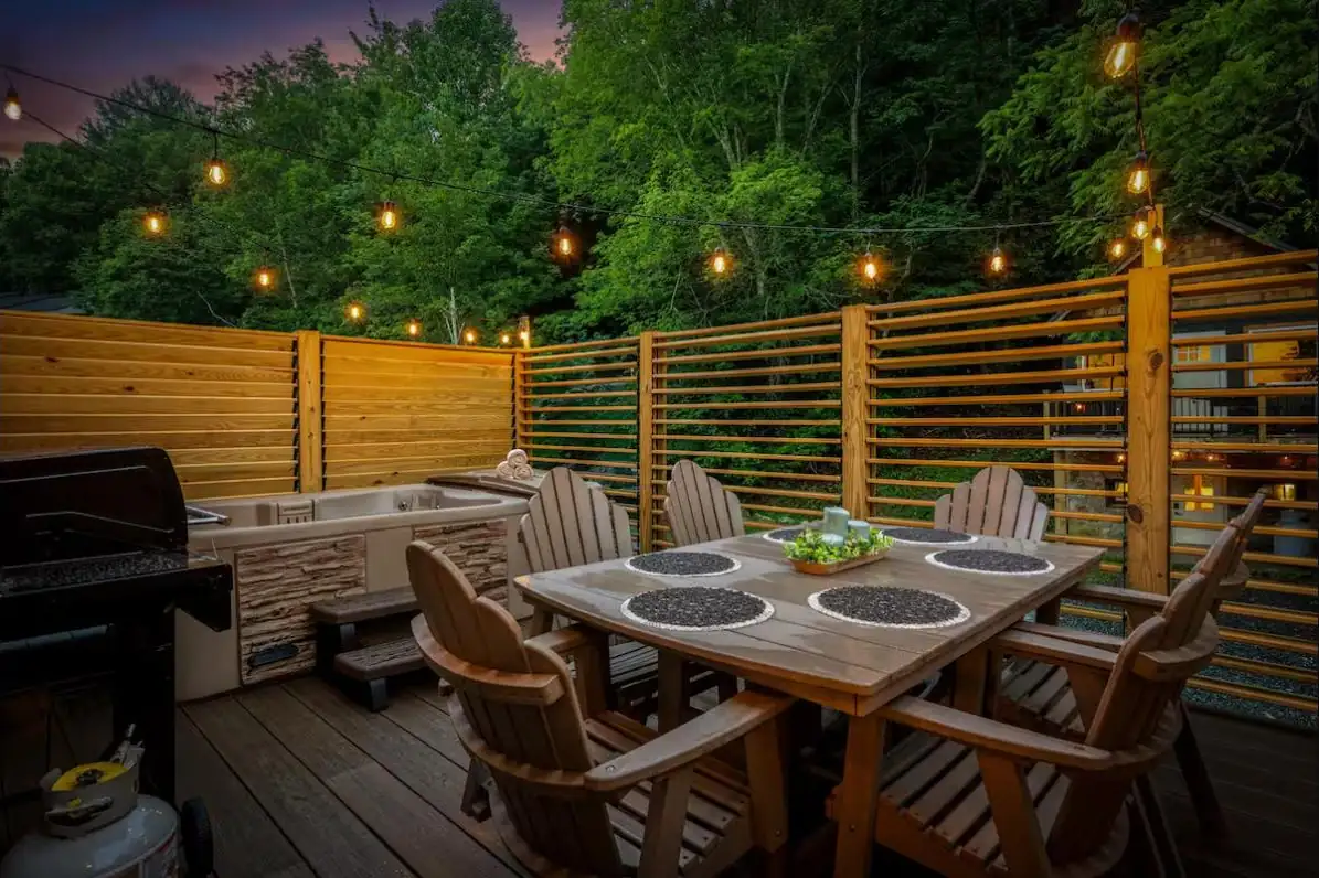 Deck dining area and hot tub wrapped in custom louvered privacy screens at dusk