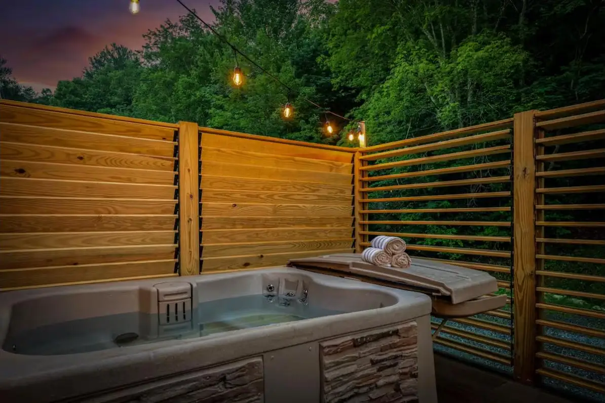 Hot tub wrapped in cedar louvered privacy walls with string lights