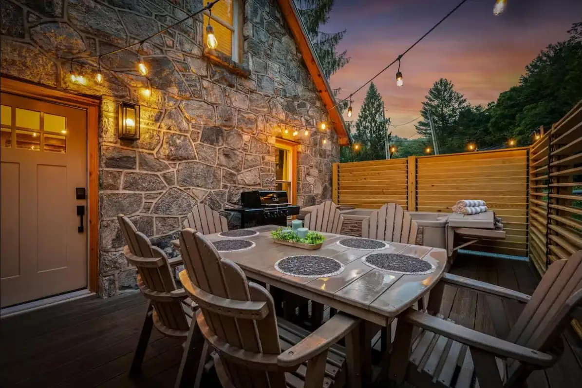 Stone cottage patio dining area enclosed by louvered privacy fencing at dusk