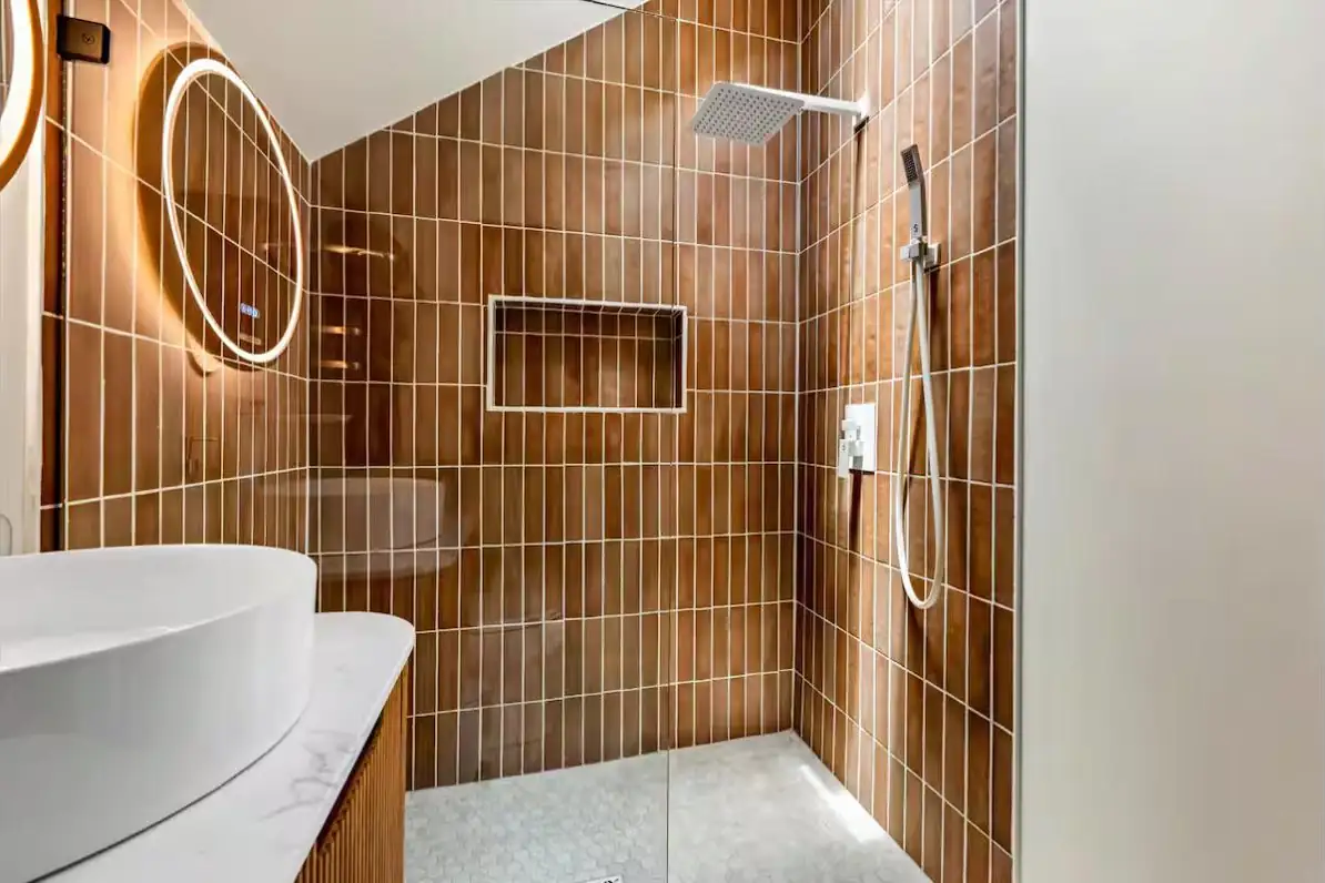 Walk-in shower in terracotta stacked tile with hex tile floor and glass surround